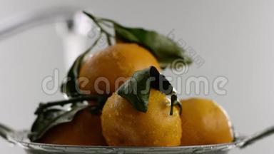 在视频中我们看到橘子，橘子躺在滑梯上，橘子上覆盖着水滴，白色的背景